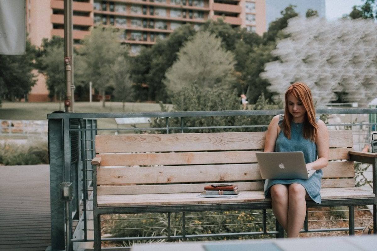 Woman on laptop on a park bench