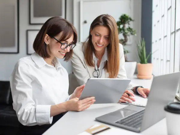 Kaksi naista istuu ja katsoo tablettia